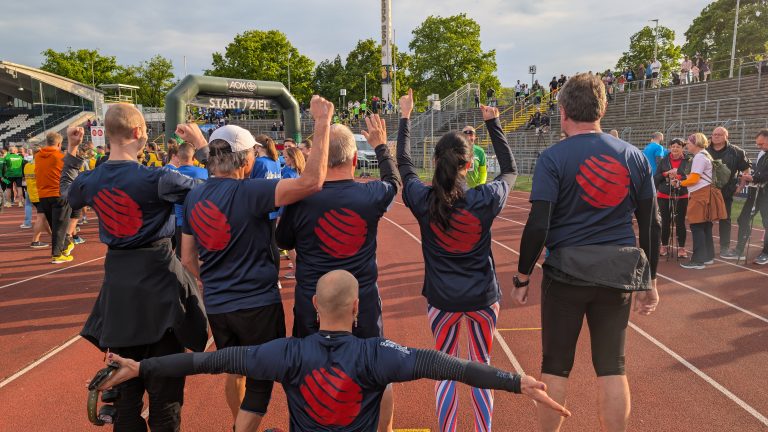 Läufer/innen accellonet beim Firmenlauf Ulm/NU; Läufer/innen von hinten jubelnd mit dem accellonet-Logo auf dem Rücken